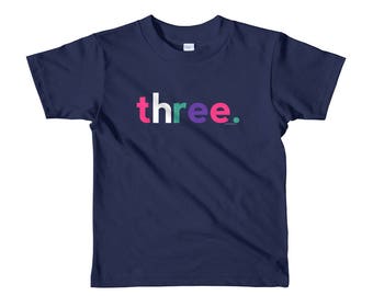 May include: A navy blue t-shirt with the word "three" printed in white, pink, and green letters.