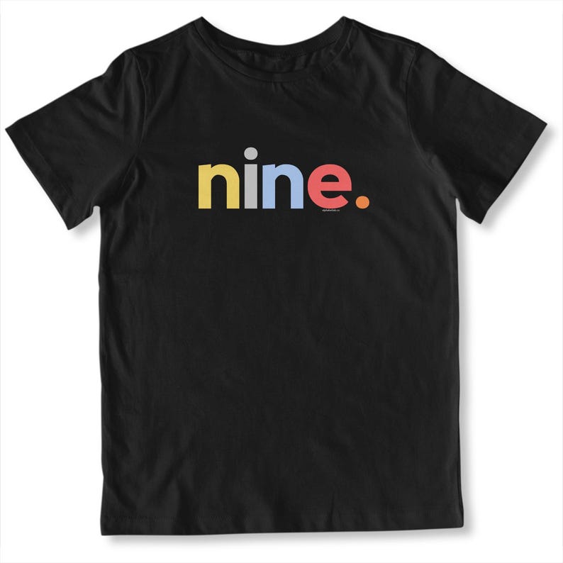 May include: Black t-shirt with the word "nine" in yellow, blue, and red. The word is centered on the shirt. The shirt is made of a soft material.