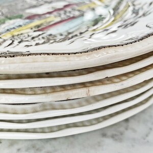May include: A stack of white ceramic plates with a brown rim and a floral design. The plates are stacked on top of each other, with the top plate showing the most detail of the design.