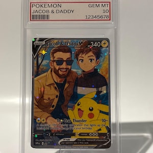May include: A Pokemon trading card featuring "Jacob & Daddy" with a Pikachu illustration. The card is encased in a protective case, graded GEM MT 10. The card's text includes "Ten-Year Thunder" and other game-related details.