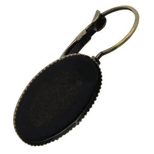 May include: A bronze oval earring with a blank setting for a cameo or other embellishment. The earring has a lever back closure.