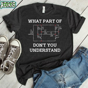 Puede incluir: Una camiseta gris oscuro con un gráfico blanco de un diagrama de circuito y el texto "WHAT PART OF DON'T YOU UNDERSTAND".