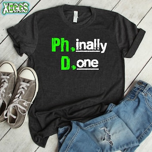 May include: A dark grey t-shirt with the text "Ph.inally D.one" in green and white lettering.