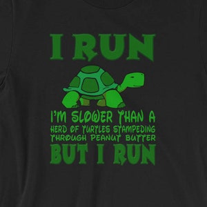 Könnte beinhalten: Schwarzes T-Shirt mit einer grünen Schildkrötengrafik und dem Text "I RUN I'M SLOWER THAN A HERD OF TURTLES STAMPEDING THROUGH PEANUT BUTTER BUT I RUN"