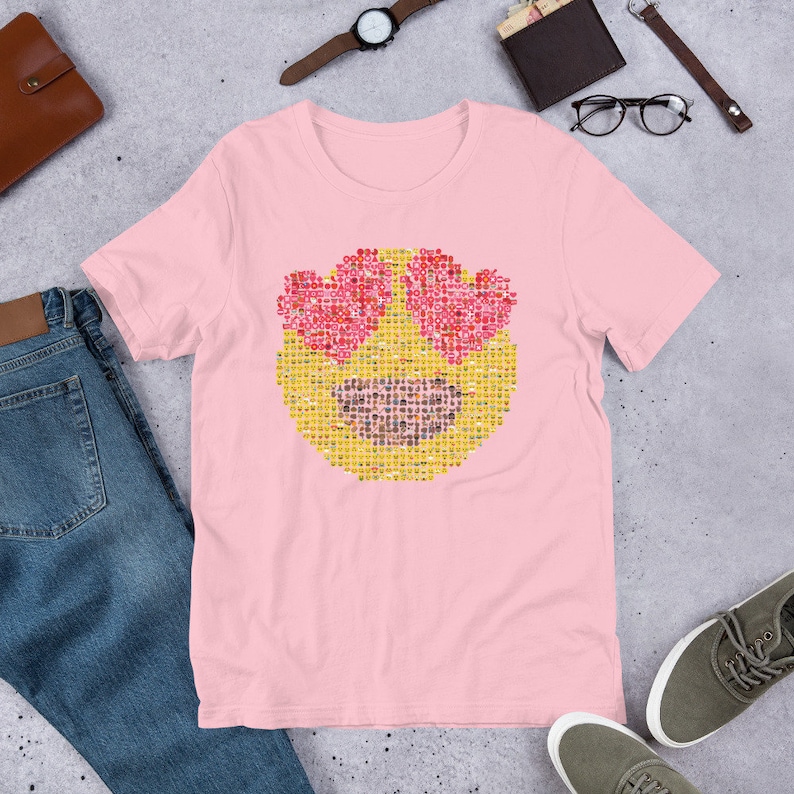 Puede incluir: Camiseta rosa claro con un gran emoji hecho de emojis m&aacute;s peque&ntilde;os. El emoji tiene ojos en forma de coraz&oacute;n y una boca sonriente. La camiseta est&aacute; hecha de un material suave.