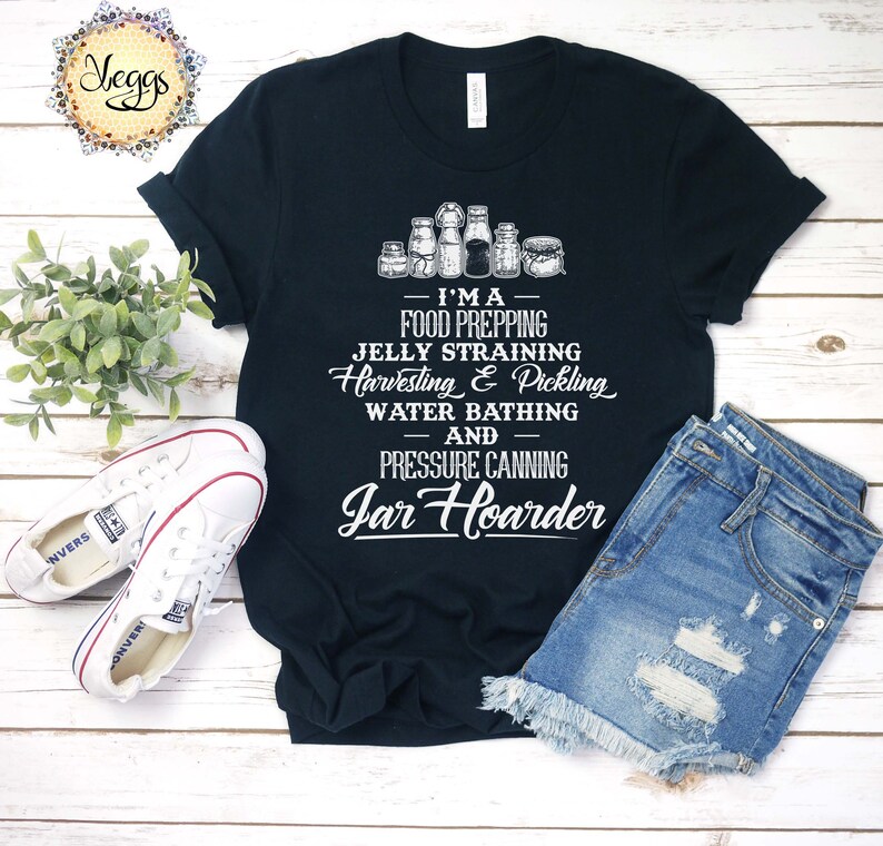 Puede incluir: Una camiseta negra con un gr&aacute;fico blanco que dice "Soy un preparador de alimentos, un colador de jalea, una cosecha y un encurtido, un ba&ntilde;o de agua y un enlatador a presi&oacute;n de tarros". El gr&aacute;fico tambi&eacute;n incluye una fila de tarros.