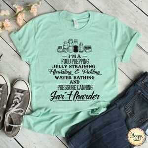 Puede incluir: Una camiseta verde claro con un dise&ntilde;o gr&aacute;fico negro que presenta frascos y el texto "I'MA FOOD PREPPING JELLY STRAINING Harvesting & Pickling WATER BATHING AND PRESSURE CANNING Jar Hoarder"