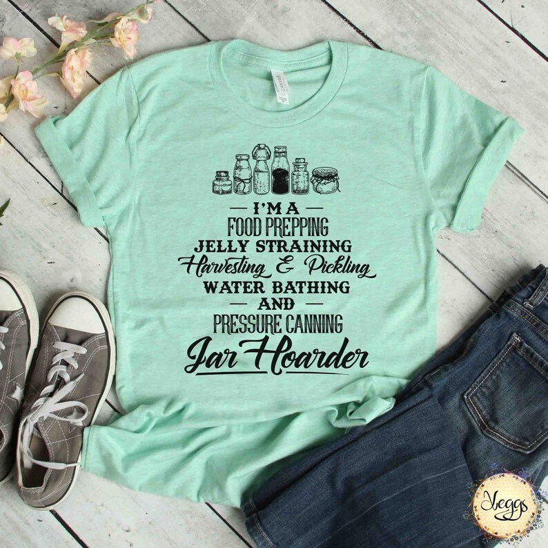 Puede incluir: Una camiseta verde claro con un dise&ntilde;o gr&aacute;fico negro que presenta frascos y el texto "I'MA FOOD PREPPING JELLY STRAINING Harvesting & Pickling WATER BATHING AND PRESSURE CANNING Jar Hoarder"