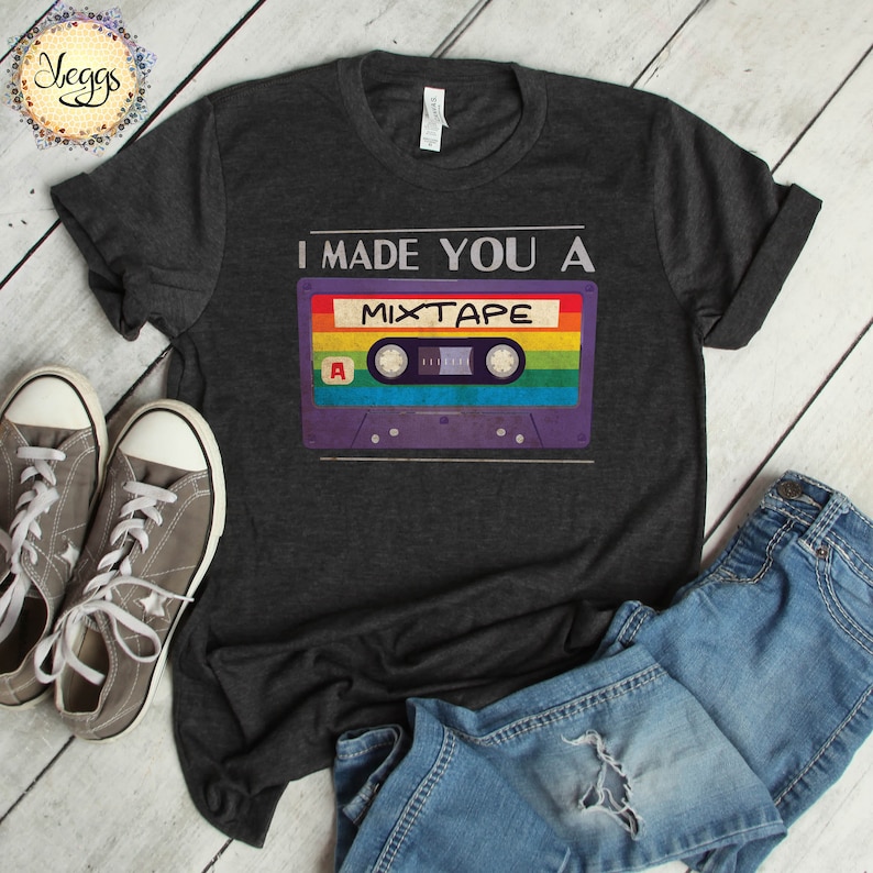 May include: A dark grey t-shirt with the text "I made you a mixtape" and a vintage cassette tape graphic with rainbow colored tape.
