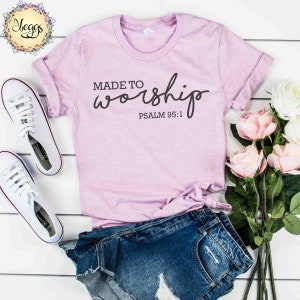 May include: A light purple t-shirt with the text "MADE TO worship" in black cursive lettering and the text "PSALM 95:1" in black below the cursive text.