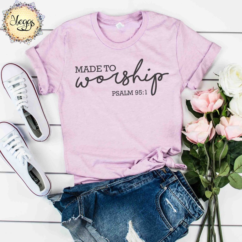 May include: A light purple t-shirt with the text "MADE TO worship" in black cursive lettering and the text "PSALM 95:1" in black below the cursive text.