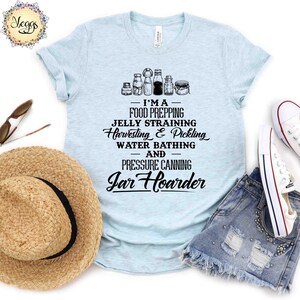 Puede incluir: Una camiseta azul claro con un gr&aacute;fico de frascos y el texto "I'MA - FOOD PREPPING - JELLY STRAINING - Harvesting & Pickling - WATER BATHING - AND - PRESSURE CANNING - Jar Hoarder"