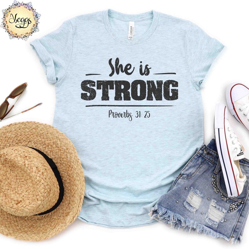 May include: Light blue t-shirt with the text "She is STRONG" and "Proverbs 31:25" printed in black.