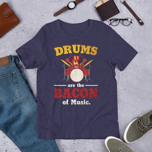 Może przedstawiać: Koszulka w kolorze granatowym z nadrukiem zestawu perkusyjnego i tekstem "Drums are the bacon of Music."