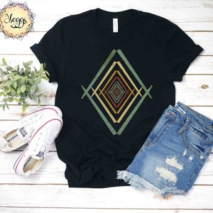 May include: A black t-shirt with a geometric design in shades of green, yellow, and orange. The design is a series of overlapping diamonds that create an optical illusion.