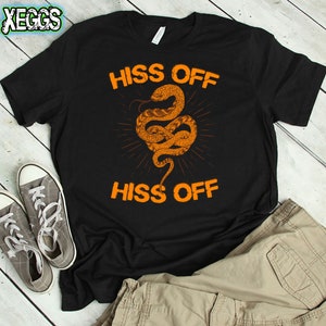 Puede incluir: Camiseta negra con un gr&aacute;fico de serpiente naranja y el texto "Hiss Off" repetido dos veces.