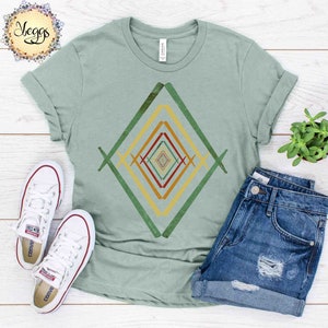 May include: A light green t-shirt with a geometric design in shades of green, yellow, orange, and red. The design is a series of overlapping diamonds.
