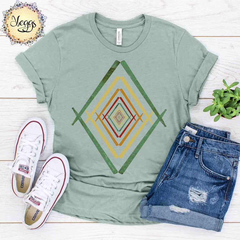 May include: A light green t-shirt with a geometric design in shades of green, yellow, orange, and red. The design is a series of overlapping diamonds.