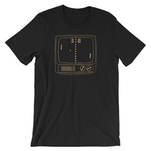 Puede incluir: Camiseta negra con una ilustraci&oacute;n de estilo retro de una consola de juegos de arcade vintage con el marcador 3:8 en la pantalla.