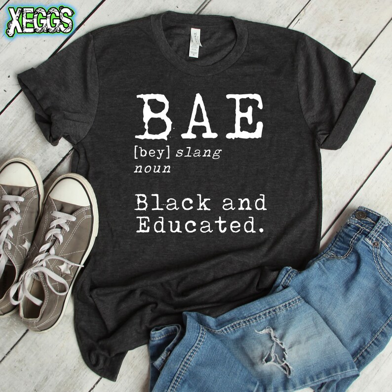 May include: A dark gray t-shirt with the word "BAE" in white block letters. The word is defined as "[bey] slang noun Black and Educated."
