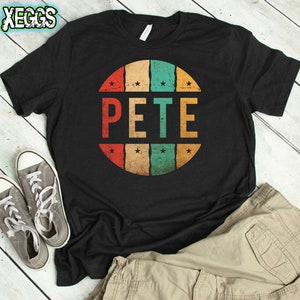 May include: Black t-shirt with a retro-style circular design featuring the name "PETE" in colorful block letters. The design has a distressed, vintage look.