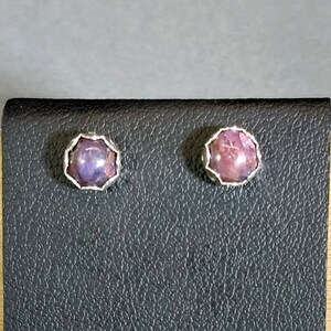 May include: A pair of silver stud earrings with purple and pink gemstone accents.
