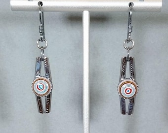 May include: A pair of silver earrings with a circular design in the center. The center design is made of layered paper in shades of brown, white, and blue.