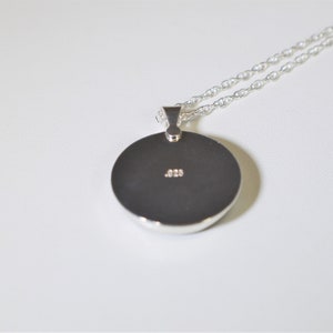 May include: Silver pendant necklace with a round disc charm. The back of the charm has the inscription .925.