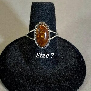 May include: A silver ring with an oval-shaped brown and gold gemstone. The ring is size 7.