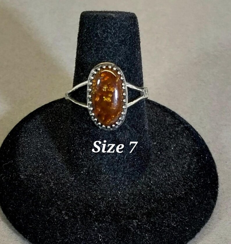 May include: A silver ring with an oval-shaped brown and gold gemstone. The ring is size 7.