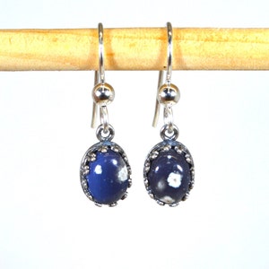 May include: A pair of silver dangle earrings with blue and white oval-shaped stones set in a silver bezel.