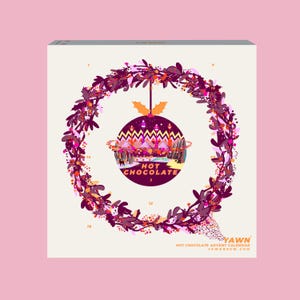Op de afbeelding: Een witte doos met een feestelijk ontwerp. Een cirkelvormig ornament met "HOT CHOCOLATE" staat in het midden, omringd door een krans van paarse bladeren en bessen. De doos is gelabeld "YAWN HOT CHOCOLATE ADVENT CALENDAR".