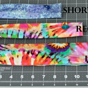 May include: Three fabric headbands in different lengths, labelled "SHORT", "REGULAR", and "LONG". The headbands are made of colourful tie-dye fabric and have a button on each end.