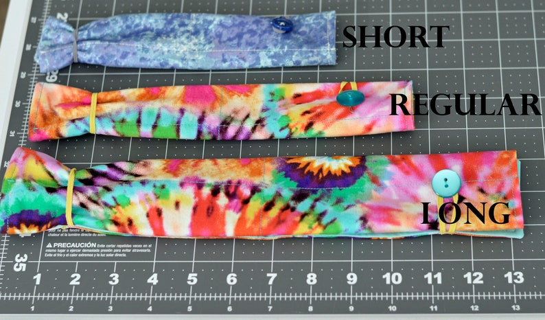 May include: Three fabric headbands in different lengths, labelled "SHORT", "REGULAR", and "LONG". The headbands are made of colourful tie-dye fabric and have a button on each end.
