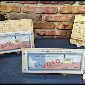 May include: Two framed Texas Sales and Use Tax Permits with the word "VOID" stamped across them. The frames are made of wood and have a rustic look. The text "Thank you! You support a small business like mine. You are supporting a Dream, a Family, and our Community." is printed on the top frame. The text "When you support a business like mine, you are supporting a Dream, a Family, and our Community. Thank you! Creations by LaLa" is printed on the bottom frame.
