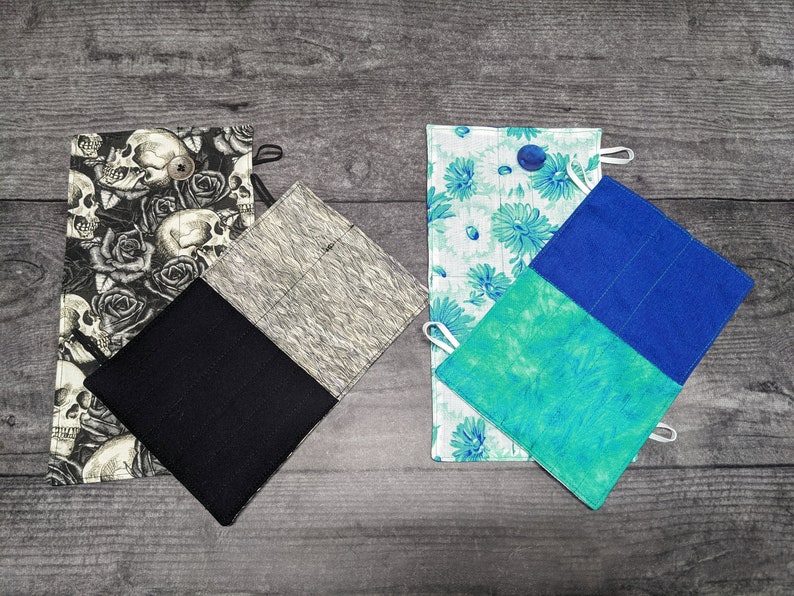 May include: Three different fabric pot holders. One is black with a skull and rose pattern, another is grey with a white pattern, and the last is blue and green with a floral pattern.