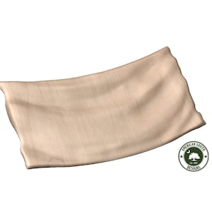 May include: A beige fabric pillow with a slightly curved shape. The pillow is made of a soft, textured material.