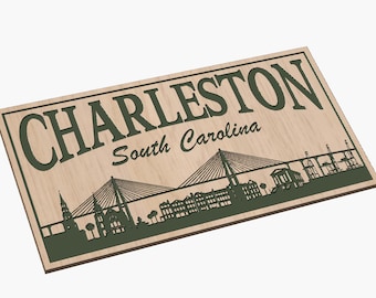 May include: Wooden sign with a green silhouette of the Charleston, South Carolina skyline, including a bridge and buildings. The text "Charleston" and "South Carolina" are also in green.