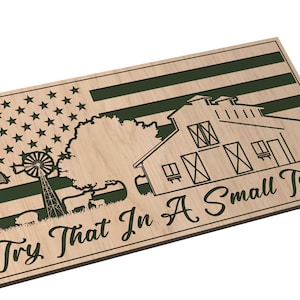 Könnte beinhalten: Ein Holzschild mit einer grünen amerikanischen Flagge, einem Scheunen, einem Baum, einer Windmühle und dem Text "Try That In A Small Town". Das Schild wird von American South Designs hergestellt.