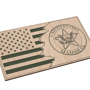Puede incluir: Una placa de madera con un diseño de bandera estadounidense verde y las palabras "United States Marshal" en un círculo.
