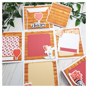 Puede incluir: Un diseño de álbum de recortes con temática de San Valentín con varios elementos decorativos. Incluye papel con estampado de corazones, un globo en forma de corazón, un conejito sosteniendo un corazón y el texto "I love you". El diseño tiene un fondo de vetas de madera.