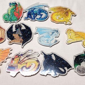 May include: A collection of colorful dragon-themed stickers. The stickers feature various dragon designs in shades of green, blue, yellow, orange, and black. Each sticker has a unique dragon illustration with detailed wings and scales.