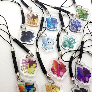 May include: A collection of 12 colorful dragon phone charms with black braided lanyards. Each charm features a different dragon design with a clear acrylic background.