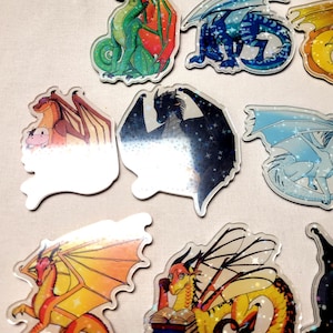 May include: A collection of colorful dragon-themed stickers. The stickers feature various dragon designs with different color schemes, including green, blue, orange, and black. Some dragons are depicted with wings and others are reading books.