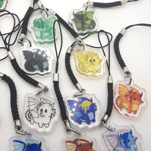 May include: A set of ten colorful dragon charm keychains. Each keychain features a pair of dragons in a clear plastic charm with a black cord.