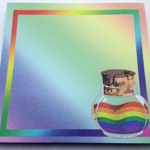 Könnte beinhalten: Ein Glasgefäß mit einem Korkstopfen, das eine regenbogenfarbene Flüssigkeit enthält. Das Gefäß befindet sich auf einem Hintergrund mit einem Regenbogenrand.