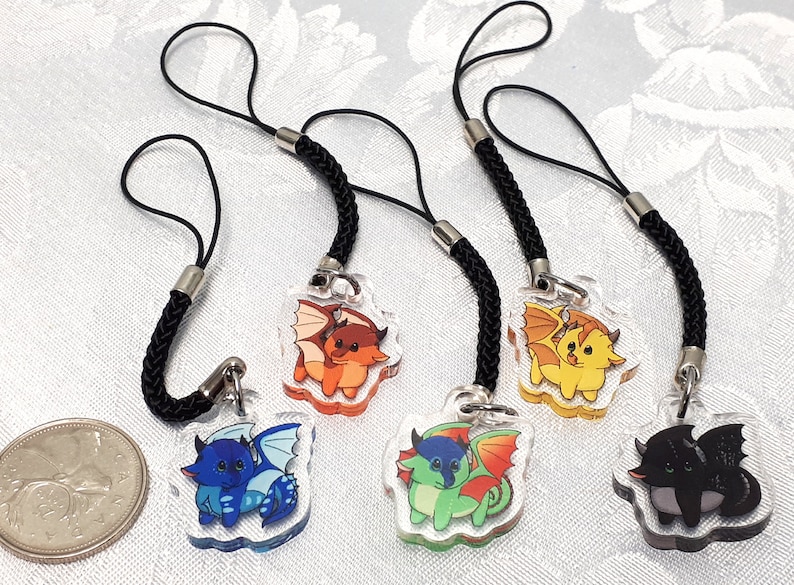 May include: Four colorful dragon phone charms with black cords. The dragons are orange, yellow, green, and black.