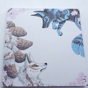 May include: A white and brown nine-tailed fox with a white and blue fox with blue and black markings. Both foxes are surrounded by pink cherry blossoms.