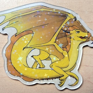 May include: A holographic sticker featuring a yellow dragon with outstretched wings. The dragon has a smiling expression and is surrounded by sparkling stars. The sticker has a clear border and is likely for decorative purposes.
