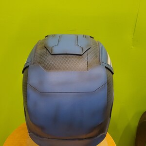May include: A blue and black helmet with a textured surface. The helmet has a raised panel on the top and a white stripe on the side.